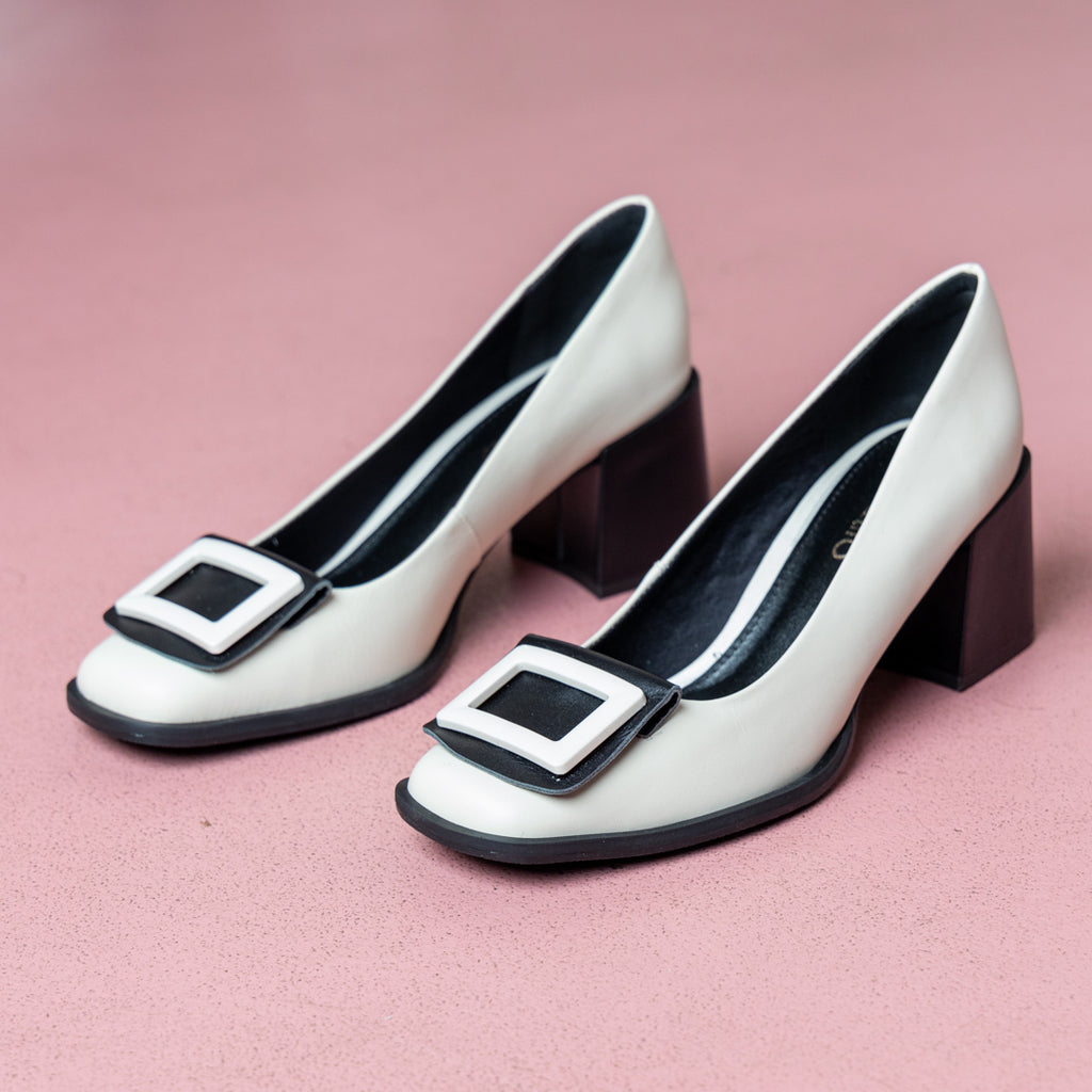 Pair of black and white heels on pink background