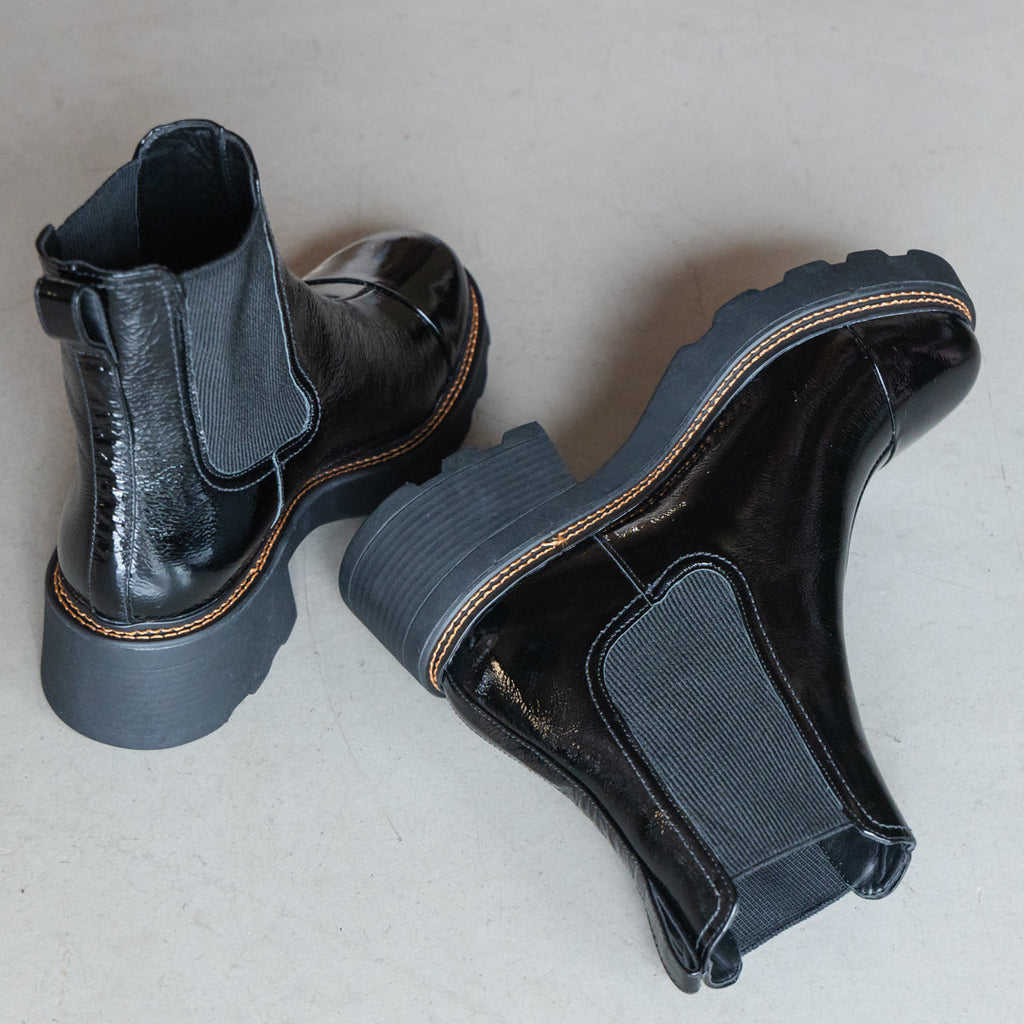 Pair of black patent boots on concrete floor