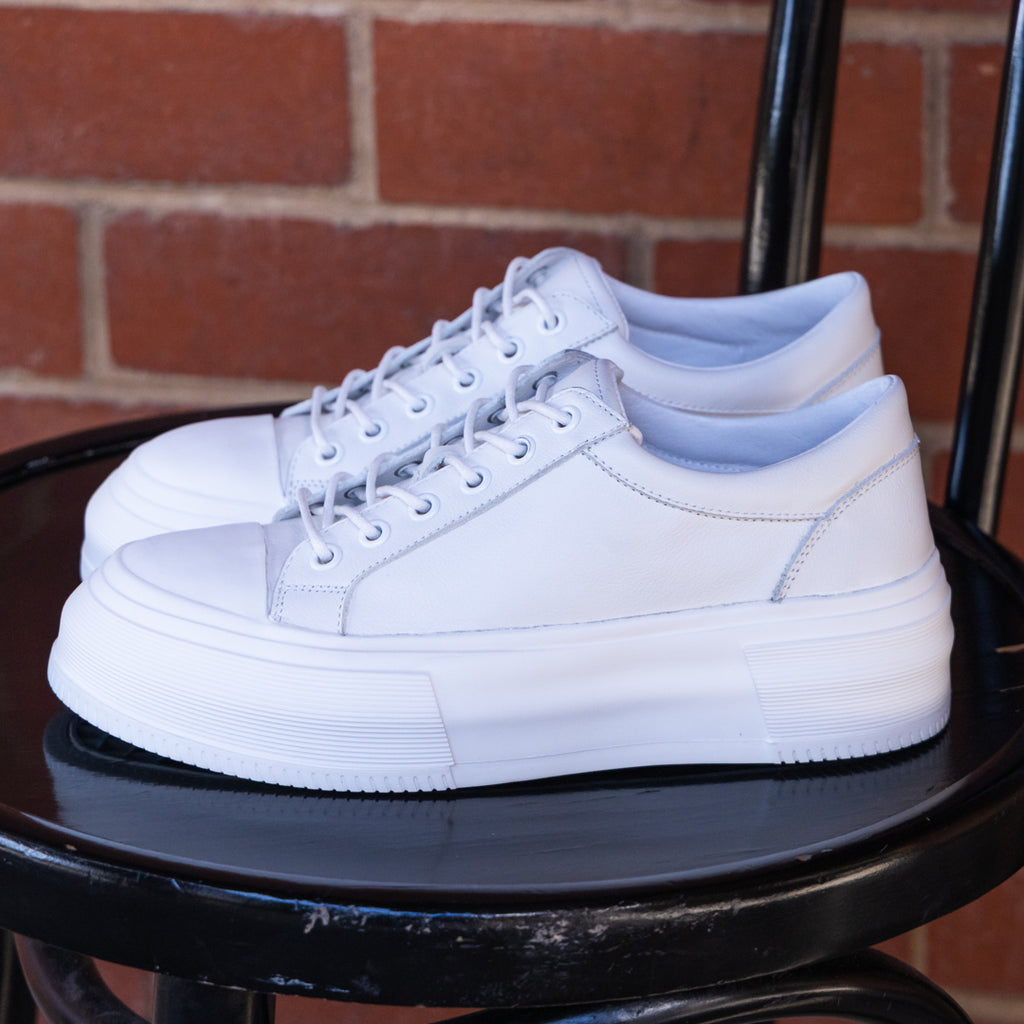 White sneakers on a black chair with red brick backgroud
